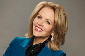 Renee Fleming smiling at the camera with her head cocked.